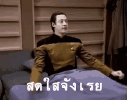 a man in a star trek uniform is sitting on a bed with a blanket .