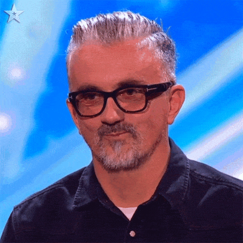 a man with glasses and a beard is sitting in front of a blue star