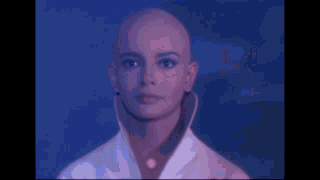 a woman with a shaved head is wearing a white coat and a red shirt .