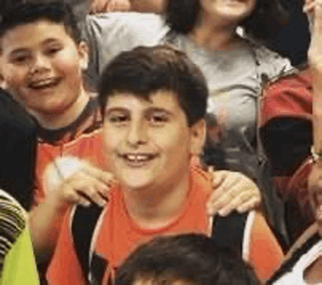 a group of children are sitting in a stadium and one of them is smiling .