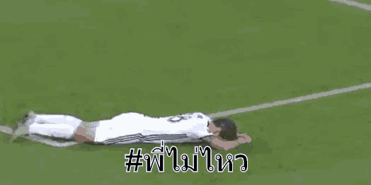 a soccer player is laying on the ground with his head in his hands .