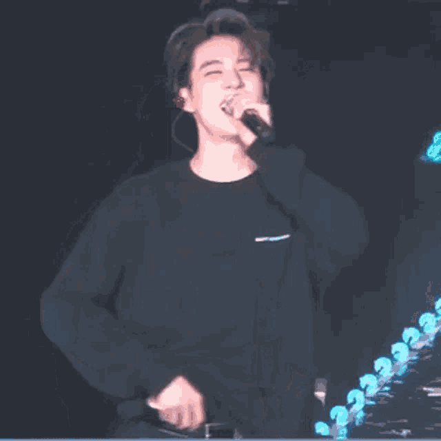 a man in a black shirt is singing into a microphone .