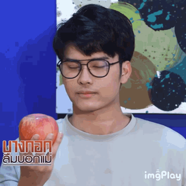a man wearing glasses holds a red apple in his hand with a watermark that says imgplay
