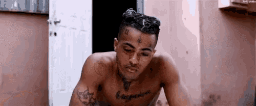 a shirtless man with a tattoo on his chest is standing in front of a door .