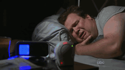 a man is sleeping next to an alarm clock that says abc on the bottom