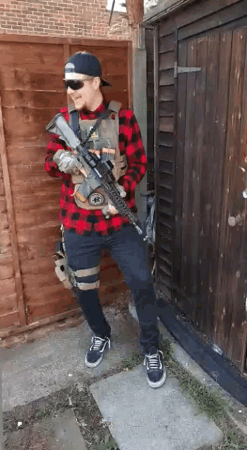 a man wearing a plaid shirt is holding a gun