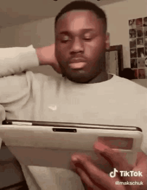 a man is holding a tablet in his hands and covering his face .