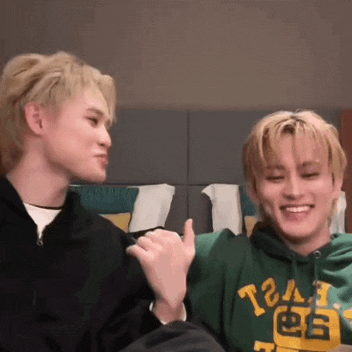 two young men are sitting next to each other on a couch and smiling .