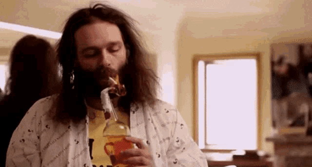 a man with a beard is drinking from a bottle