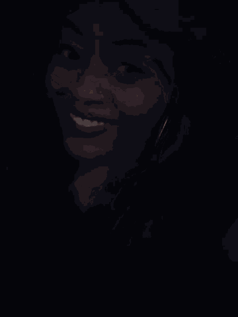 a woman with red lipstick and a nose ring smiles in the dark