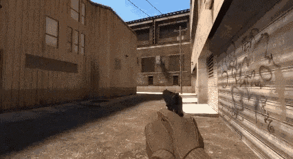 a person holding a gun in front of a building with graffiti on it .