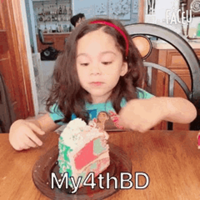 a little girl is sitting at a table eating a slice of birthday cake .