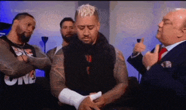 a man with a bandage on his arm is standing in front of a man in a suit .