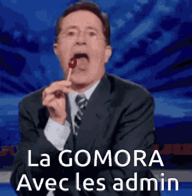 a man in a suit and tie is eating a lollipop with the words la gomora avec les admin written below him
