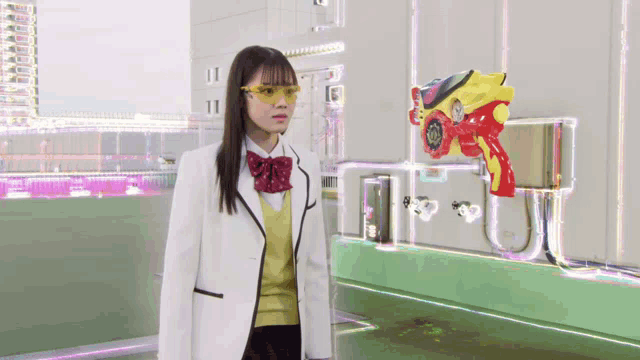 a girl in a white jacket and yellow glasses stands in front of a red toy gun