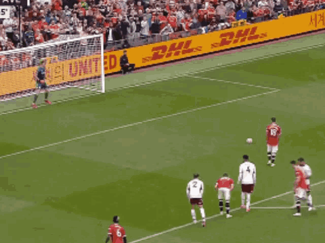 a group of soccer players on a field with dhl advertisements behind them