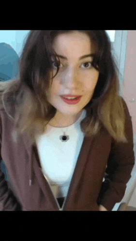 a close up of a woman wearing a brown jacket and a white shirt