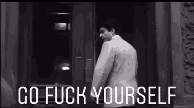 a man is standing in front of a door with the words `` go fuck yourself '' written on it .