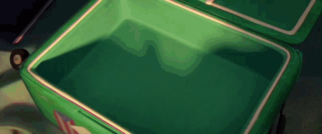 an empty green suitcase is sitting on a table with the lid open .