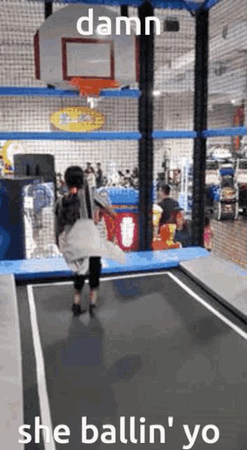 a woman is jumping on a trampoline with the words damn she ballin ' yo written on the bottom