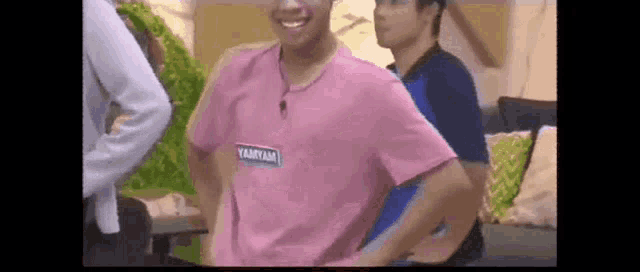 a man in a pink shirt is dancing in a room .