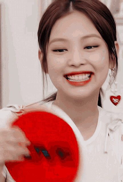 a woman is smiling and holding a red heart that says i love you on it