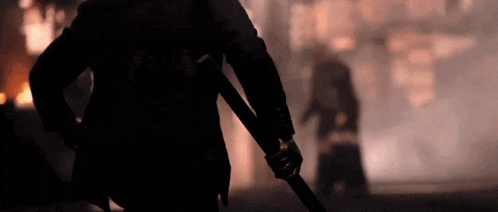 a silhouette of a man holding a sword with a blurred background