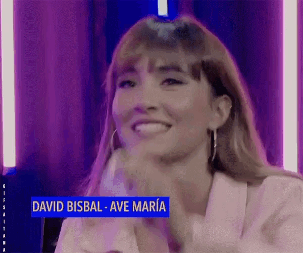 a woman is smiling in front of a sign that says david bisbal