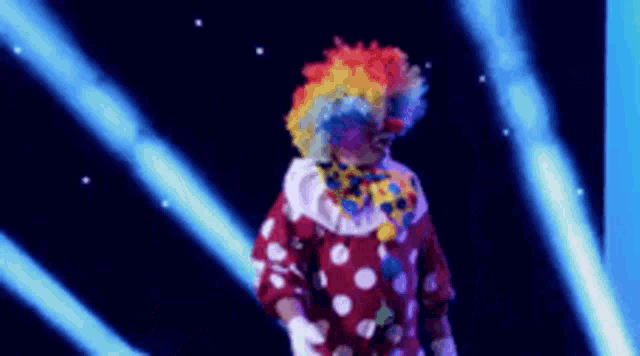 a man in a clown costume is standing in front of a blue light beam .