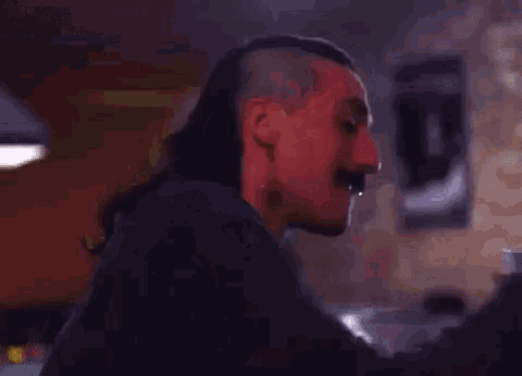 a man with long hair and a mustache is drinking from a large beer mug .