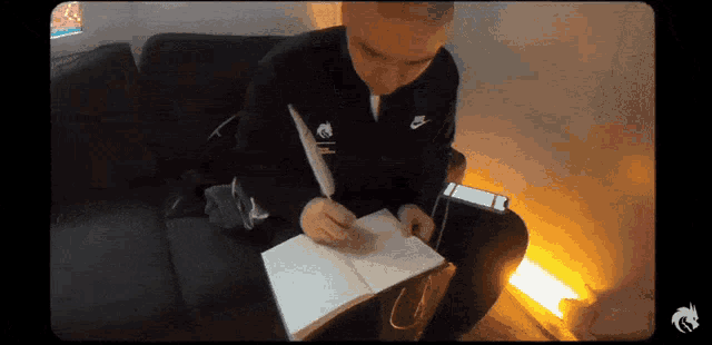 a man sitting on a couch writing in a notebook