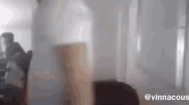 a blurry picture of a person standing in a room behind a glass wall .