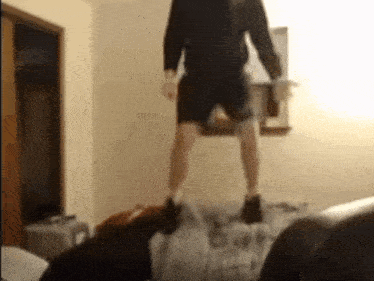 a man in shorts is jumping on a bed in a room