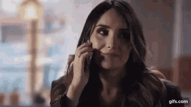 a woman is talking on a cell phone while sitting at a table in a restaurant .