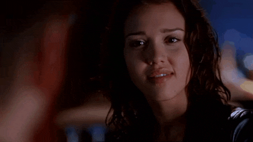 a close up of a woman 's face in a dark room with a man in the background .