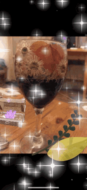 a wine glass with flowers in it is surrounded by sparkles
