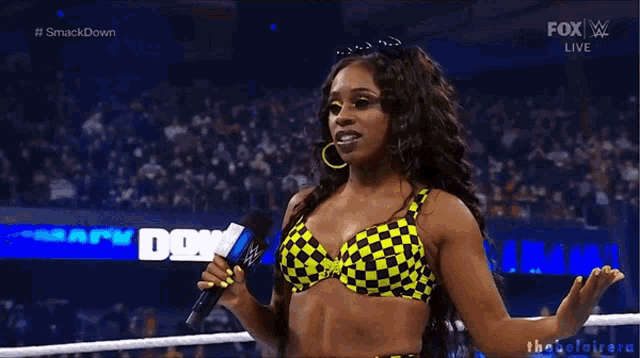 a woman in a yellow and black bikini is holding a microphone .