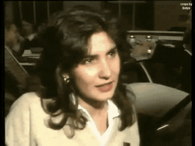 a woman in a sweater and white shirt is talking to someone in a room .