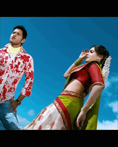 a man in a red shirt stands next to a woman in a green skirt