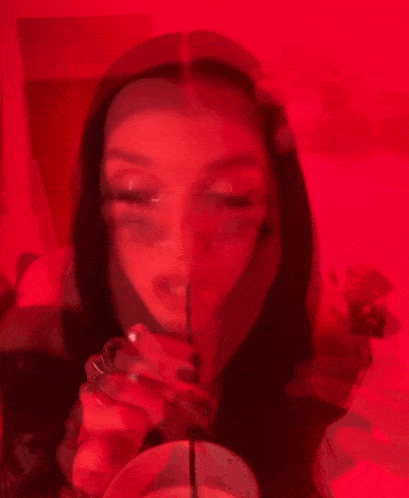 a woman is drinking through a straw in front of a red wall .