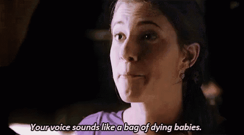 a woman in a purple shirt is talking to a man in a dark room .