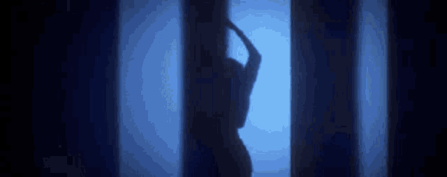 a silhouette of a woman dancing in front of a blue light .
