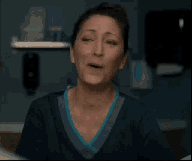 a woman in a scrub top is crying in front of a toilet paper dispenser