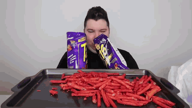 a man is eating a bag of cheetos and a bag of doritos .