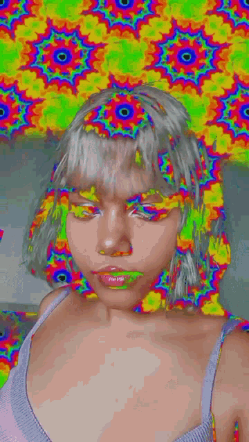 a woman is taking a selfie with a colorful background on her face .