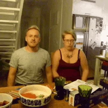 a man and woman sit at a table with bowls of food