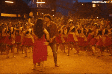 a man and woman are dancing in front of a crowd with the words mightymategifs on the bottom right