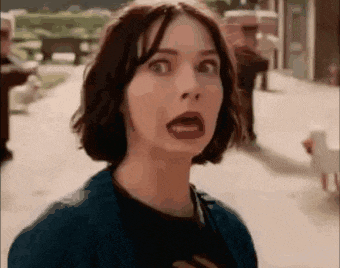 a woman with short hair is making a surprised face while standing on a street .