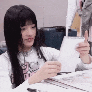 a girl with long black hair is holding a piece of paper with the letter s on it
