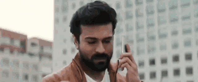 a man with a beard is talking on a cell phone in a city .